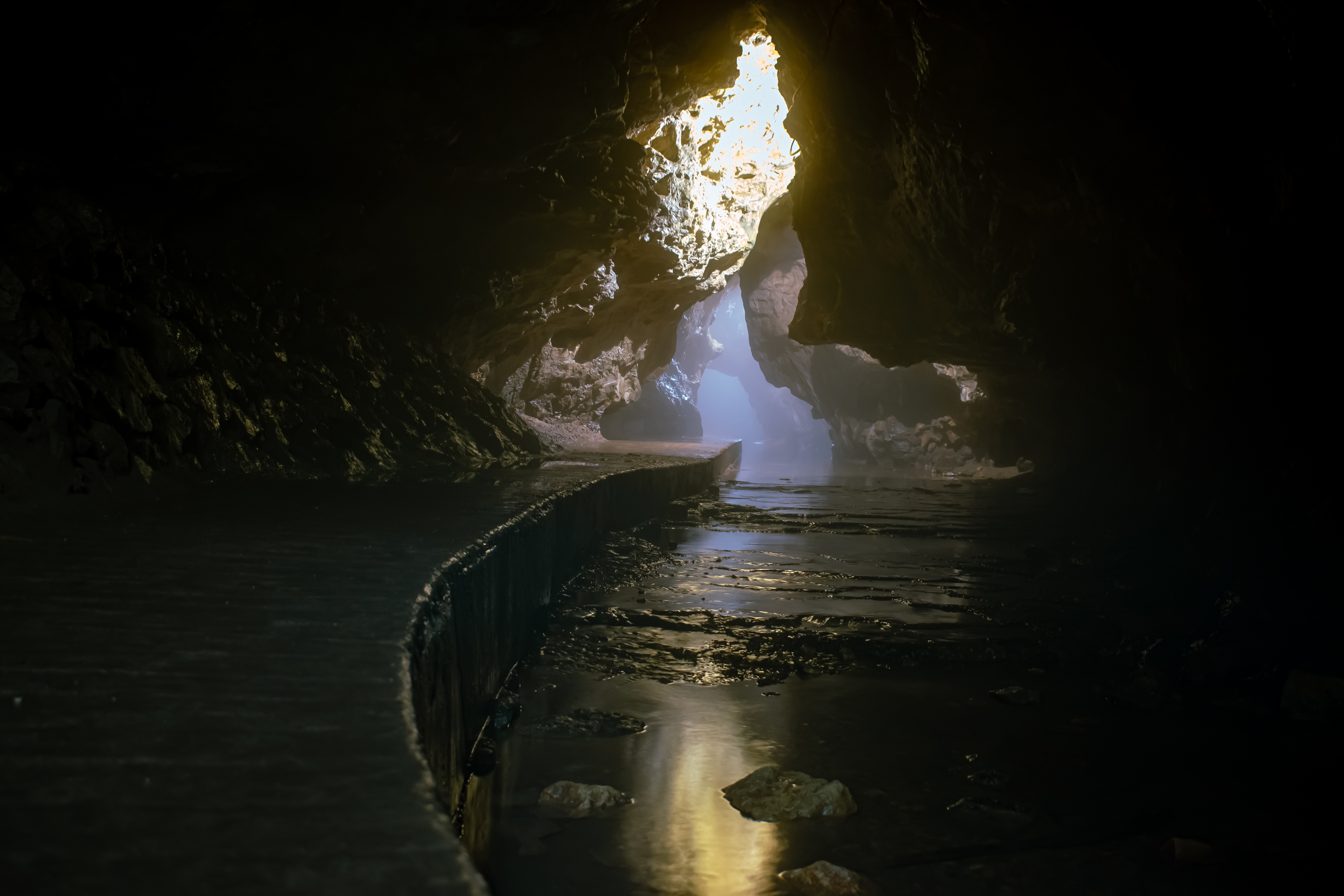 Cave interior with water and light streaming from an opening